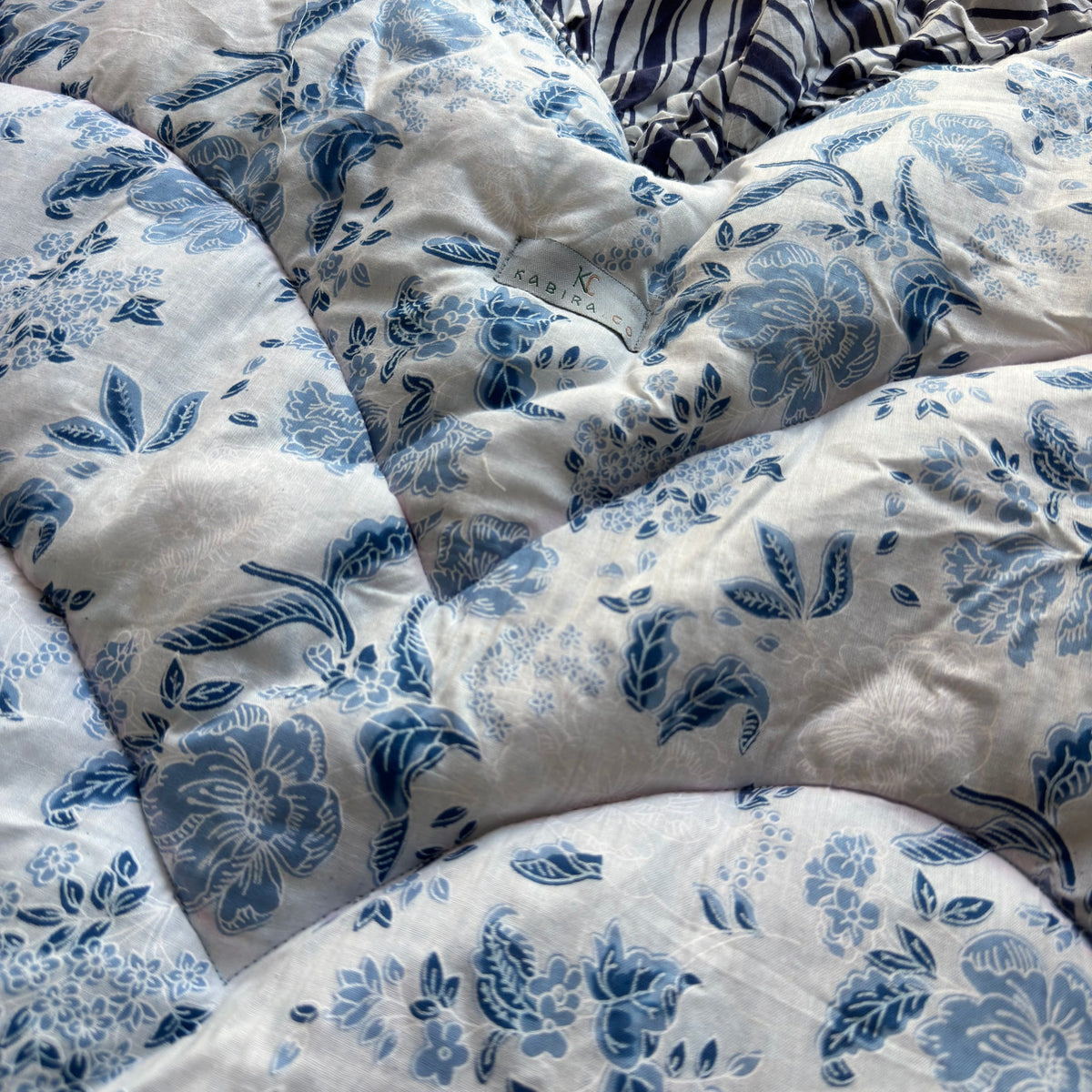 Close-up of blue floral toile flowers and leaves on the quilted mat