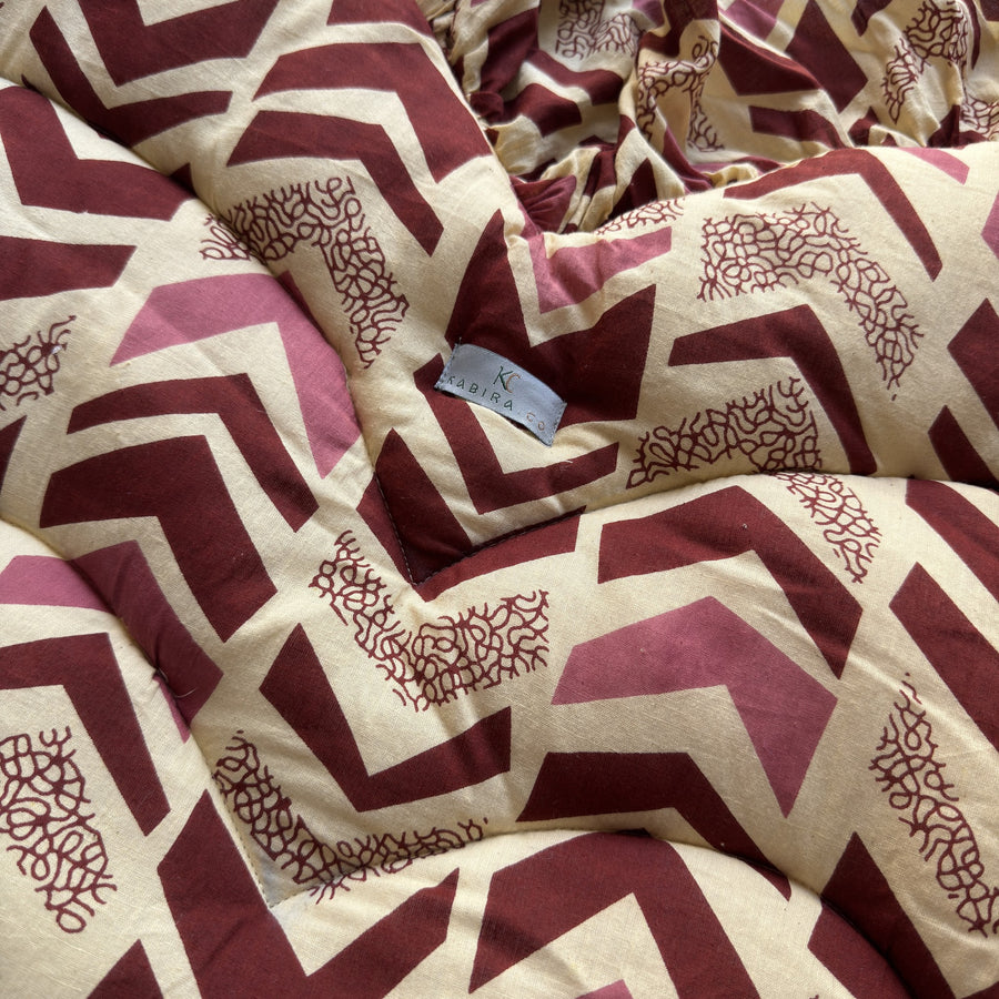 Close-up of the maroon and pink chevron print and padded quilting with a small Kabira label
