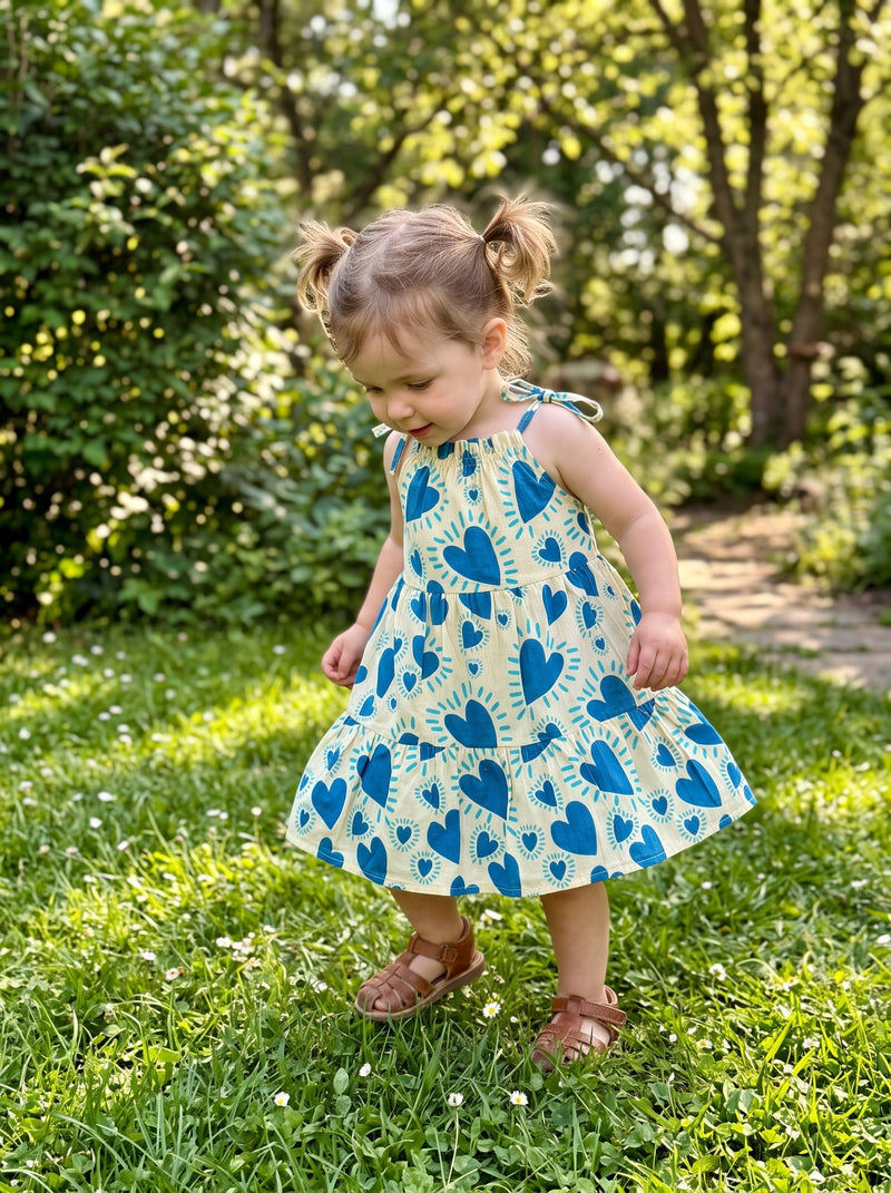 Toddler in the Blue Heart tiered frock in a garden (styled image)
