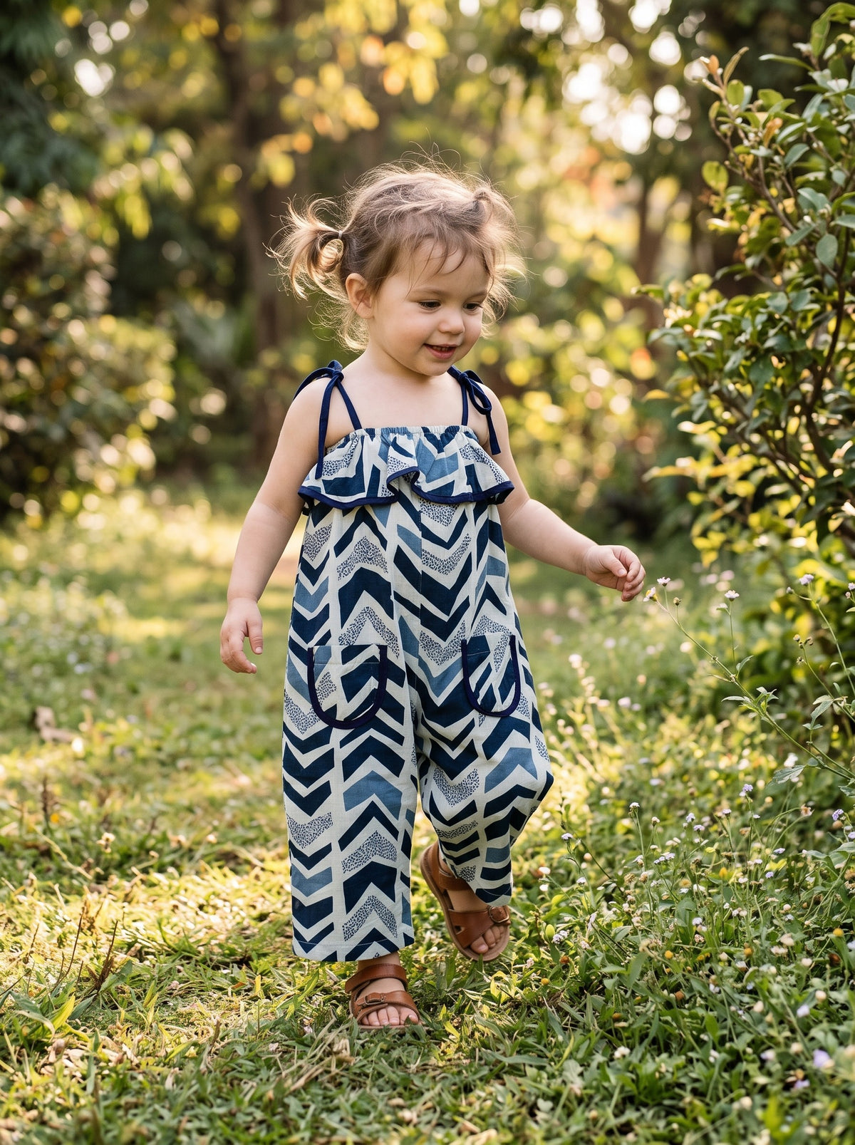 Toddler in the Indigo Chevron jumpsuit in a garden (styled image)